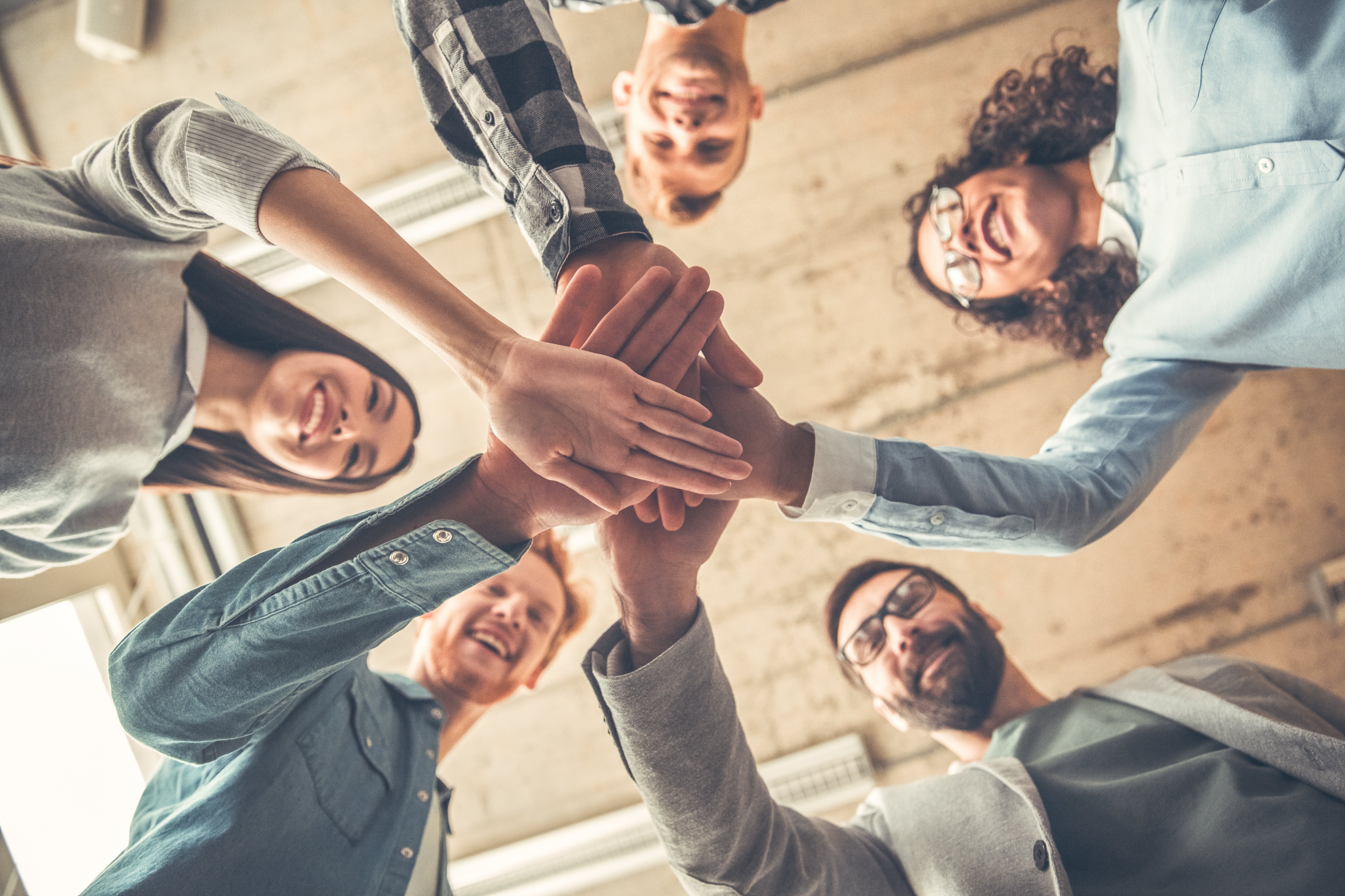 Group of young people clasping their hands