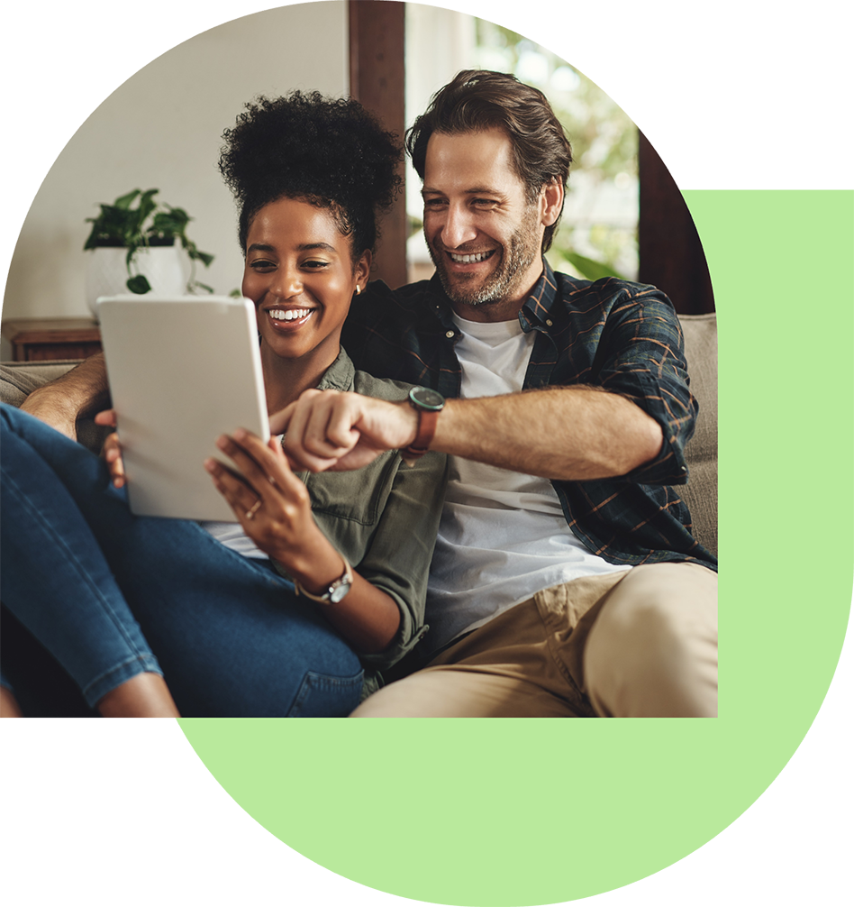 Zwei Personen sitzen auf dem Sofa und schauen auf ein Tablet