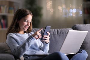 Young woman with Smartphone and Laptop_AdobeStock_295727664