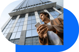 Mann mit Smartphone vor Bürogebäude