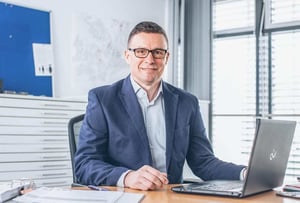 Foto von Markus Risch mit Laptop am Schreibtisch sitzend